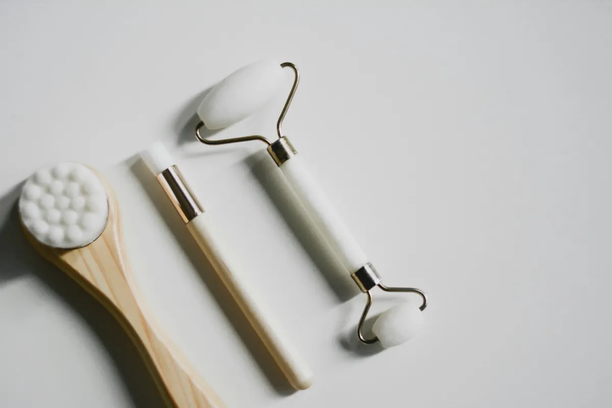 A facial cleansing brush and two face rollers on a white surface