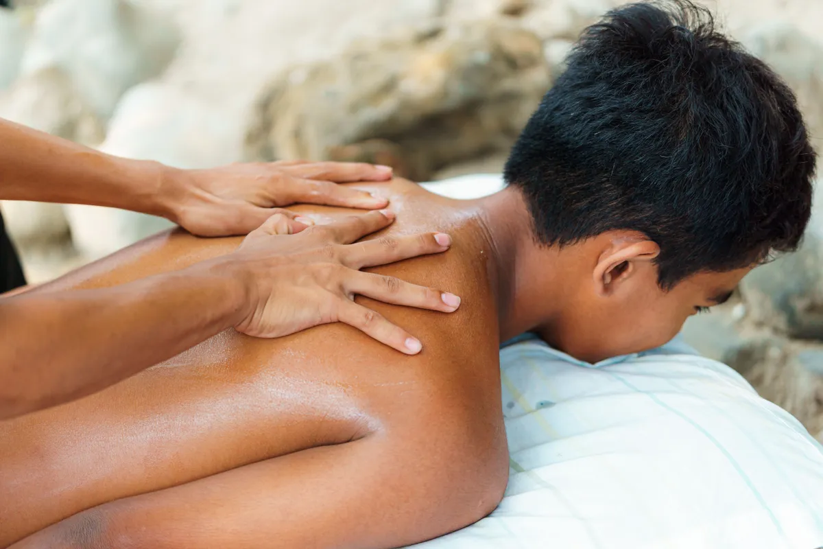 A man lying face down while a therapist massages his shoulders