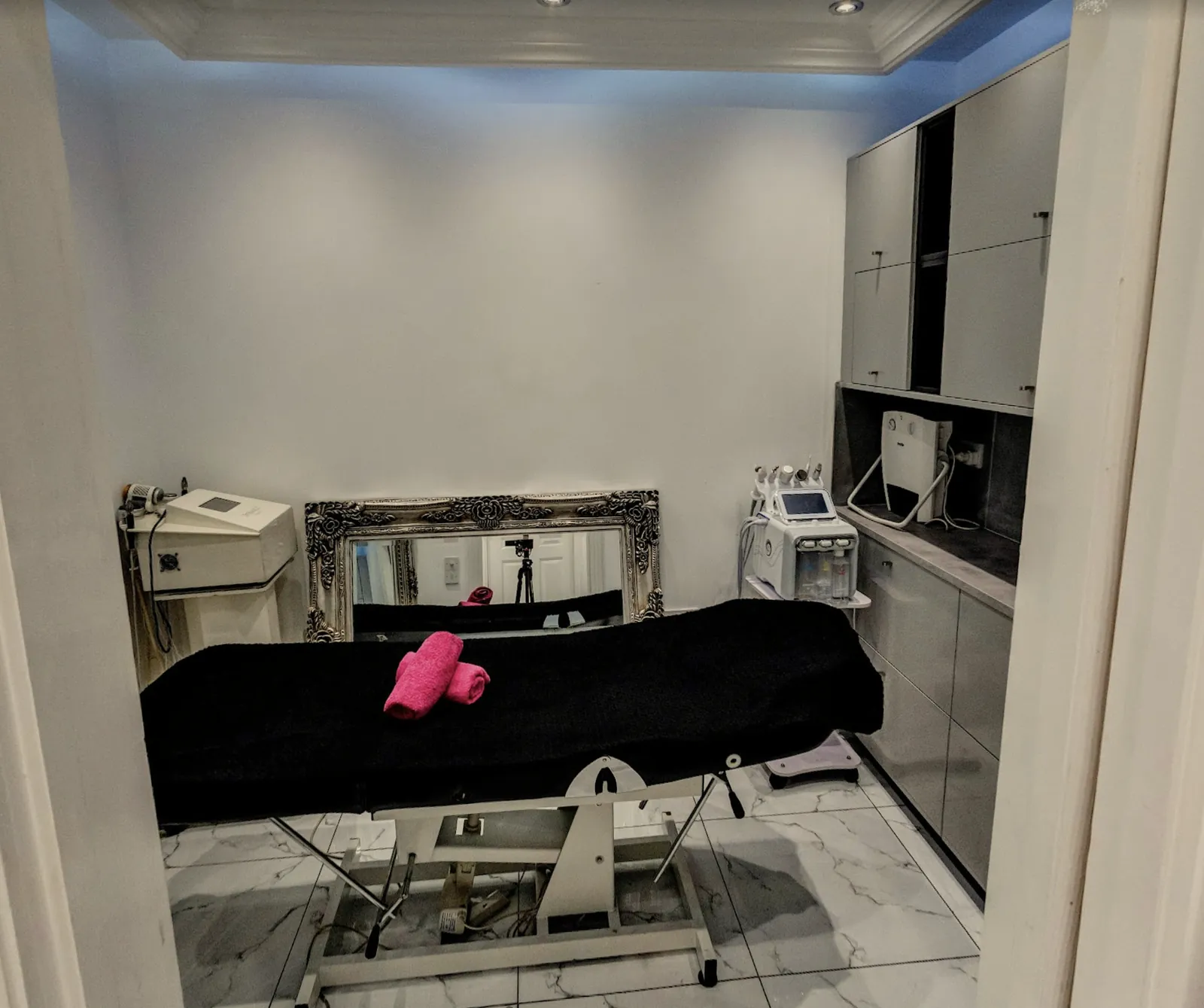 The skin clinic treatment room, with a couch, skin devices and an ornate mirror