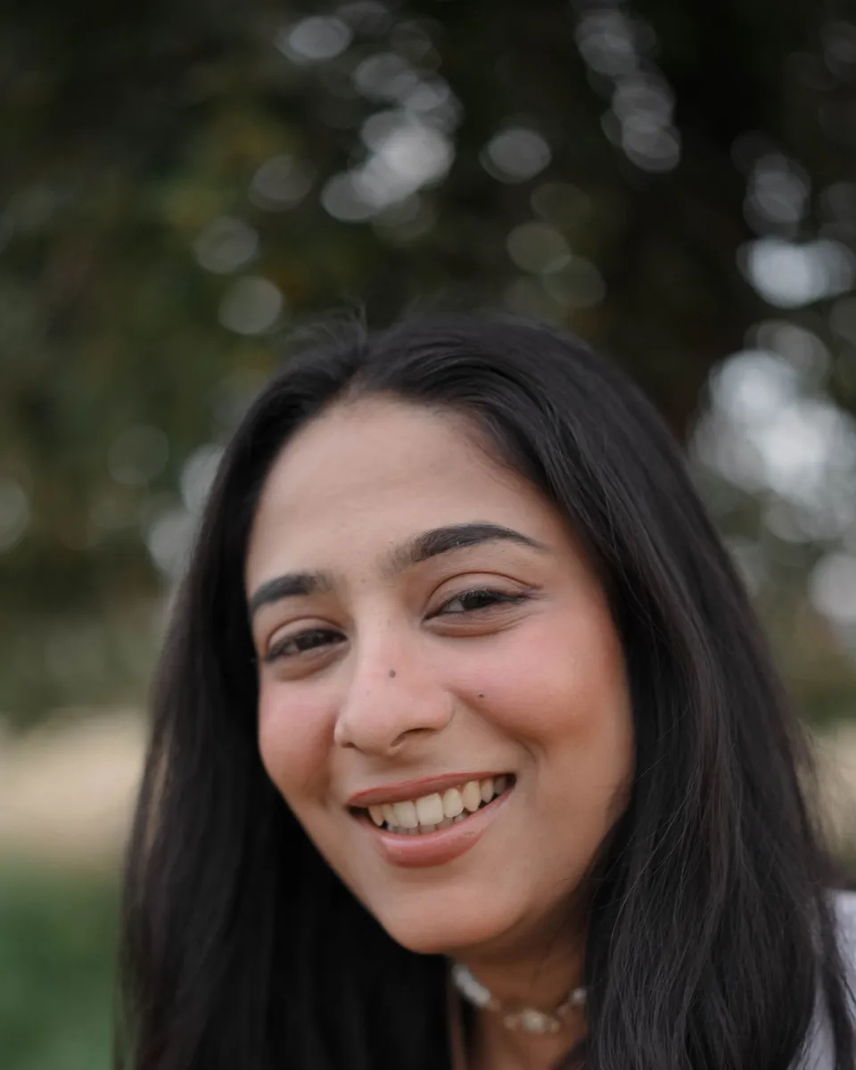 A smiling woman with long dark hair, photographed outdoors